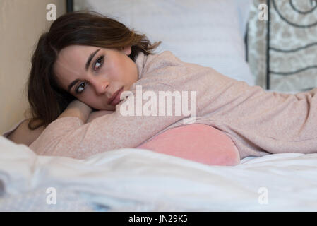 Thoughtful woman lying on bed at home Stock Photo