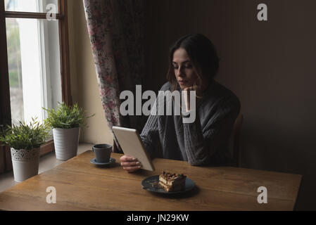 Woman using tablet computer while by window at home Stock Photo