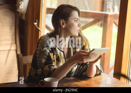 Thoughtful woman using digital tablet at home Stock Photo