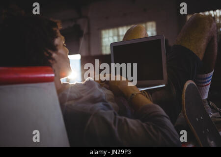Rear view of man using laptop in skateboard arena Stock Photo