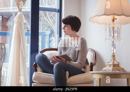 Thoughtful woman using digital tablet at home Stock Photo
