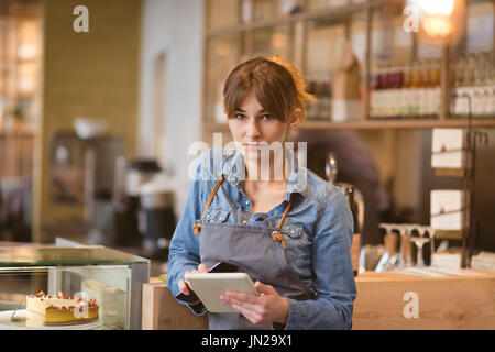 Portrait of waitress using digital tablet in cafÃƒÂ© Stock Photo