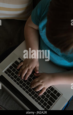 Overhead view of boy using laptop while sitting on sofa at home Stock Photo