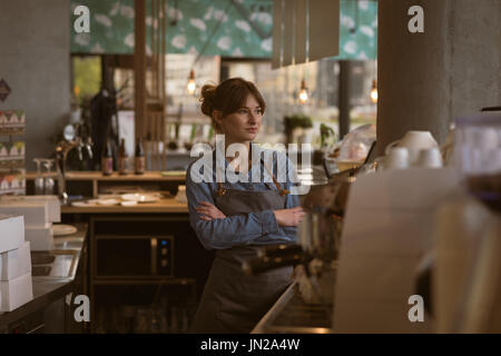 Waitress standing with arms crossed in cafe Stock Photo