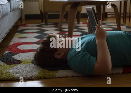 Side view of boy using digital tablet while lying on carpet at home Stock Photo