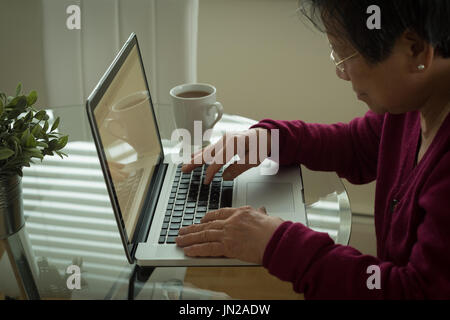 High angle view of senior woman using laptop at table Stock Photo