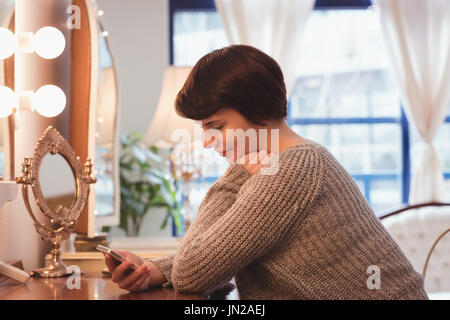 Young woman using mobile phone at home Stock Photo