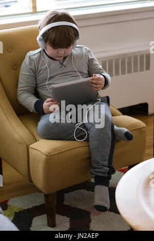 High angle view of boy wearing headphones while using tablet computer at home Stock Photo
