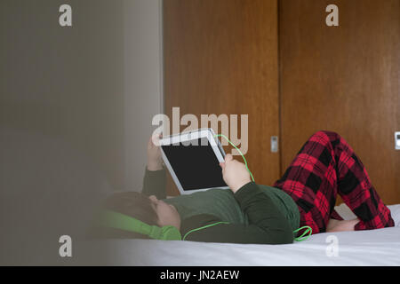 Boy using tablet computer while lying on bed at home Stock Photo