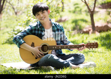 Young man playing the guitar on the grass Stock Photo