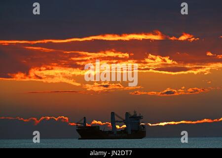 The sun rises over the general cargo ship HHL Valparaiso at Tynemouth. Stock Photo