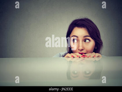 worried woman looking at something peeking from under the table Stock Photo