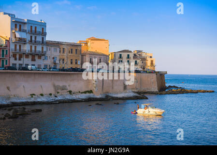 Sicily bay, view at sunset of a family relaxing on a leisure boat in a bay to the south of Ortigia Island (Syracuse / Siracusa) Sicily,