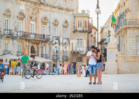 Couple looking phone Europe, view of a young tourist couple look at a phone while standing in a piazza in a Mediterranean city. Stock Photo
