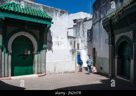 Morocco, North Africa: muslim men walking near the mosque in Place Aissawa, Aissawa Square, in the Medina area of the old town of Tangier Stock Photo