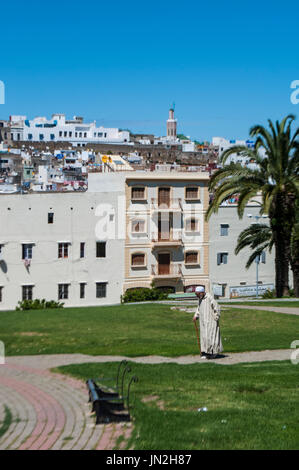 Muslim man walking in the Jardins de La Mendoubia, the Mendoubia Gardens, a famous public park in the center of Tangier, with view of the skyline Stock Photo