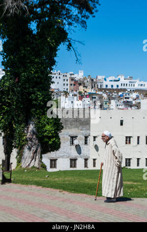 Muslim man walking in the Jardins de La Mendoubia, the Mendoubia Gardens, a famous public park in the center of Tangier, with view of the skyline Stock Photo