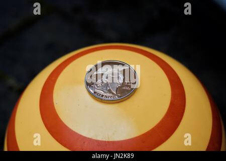 Digital currency physical gold titan bitcoin coin on yellow circle background. Stock Photo
