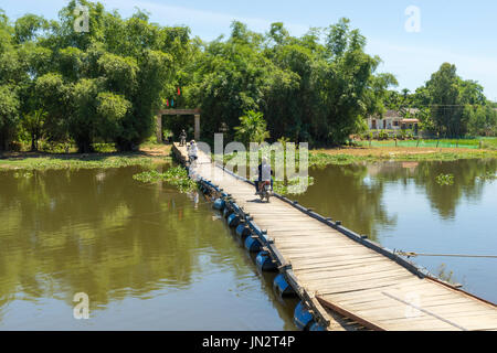 Moped riding across rustic floating bridge over Thu Bon River in rural Vietnam outside Hoi An Stock Photo