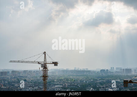 Construction cranes aerial view with the city in the background on a cloudy day, Chengdu, Sichuan Province, China Stock Photo