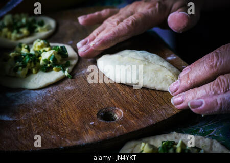 Grandma cooks pies. Home cooked food. omemade cakes of the dough in the women's hands. The process of making pie dough by hand Stock Photo