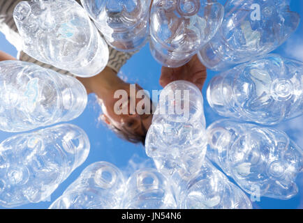 Smiling woman recycling plastic water bottles looking up POV in New Zealand, NZ Stock Photo