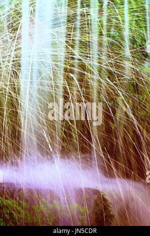 Shinning drops. Cascade of small weir on mountain stream, big mossy boulders. Stock Photo