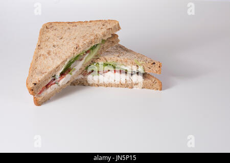 A fresh, healthy wholegrain bread chicken salad sandwich sliced into triangles and stacked on a plain white background with copy space. Stock Photo