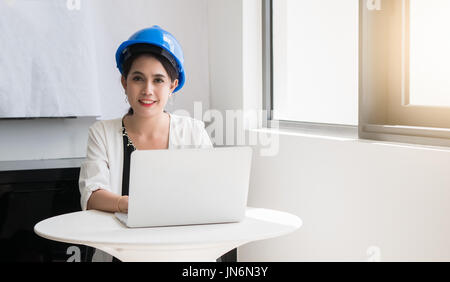 Female engineers wearing helmets and used a computer to plan construction in construction or engineer concept Stock Photo