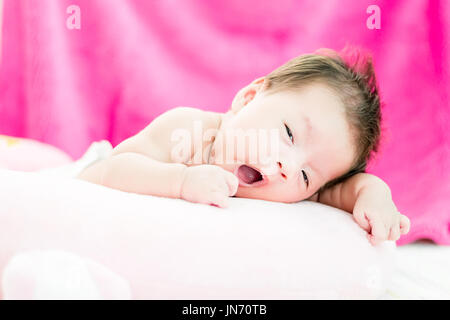 Portrait of a little adorable infant baby girl yawning before sleep on the bed indoors Stock Photo