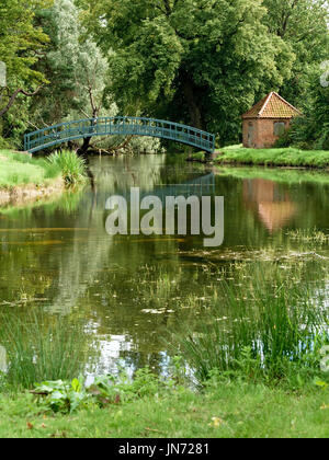 Pretty green single arch wooden pedestrian footbridge over the lake in the grounds of Doddington Hall Estate, Lincolnshire, England, UK Stock Photo