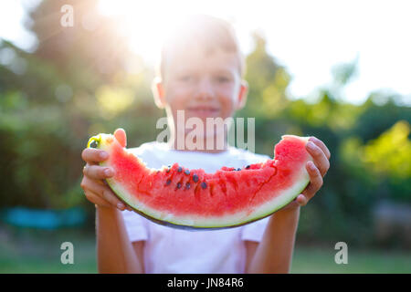 Little caucasian boy holding slice of watermelon in sunset Stock Photo