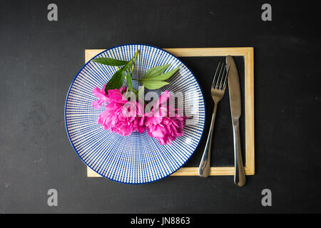 Summer table setting with bright peonies on dark rustic table with copyspace Stock Photo