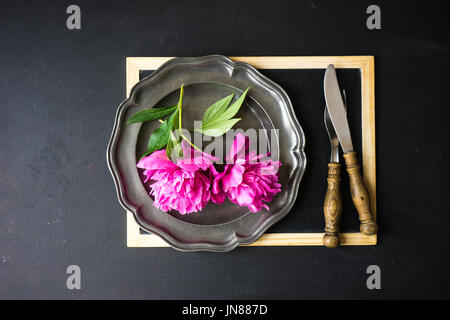 Summer table setting with bright peonies on dark rustic table with copyspace Stock Photo