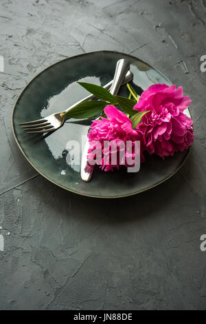 Summer table setting with bright peonies on dark rustic table with copyspace Stock Photo