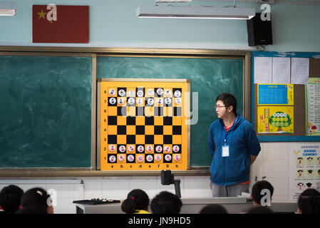 Teacher giving a chess lesson to children in a chinese classroom Stock Photo