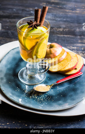 Apple cider with cinnamon sticks and fresh organic apples on dark wooden background Stock Photo