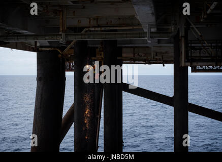 An industrial rope access (IRATA) welder, cutting a caisson on a north sea oil and gas rig. credit: LEE RAMSDEN / ALAMY Stock Photo