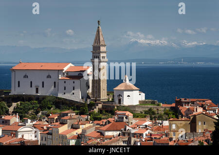 Piran Slovenia with St George's Cathedral belfry and baptistery on the Gulf of Trieste with snow capped Kanin mountains and distant Monfalcone Italy Stock Photo