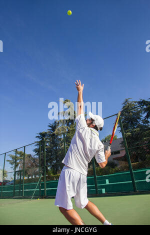 Professional tennis player is doing a kick tennis on a tennis court on a sunny summer morning. He is dressed in sportswear. Stock Photo