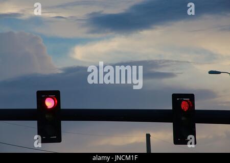 Two Red lluminated Traffic Lights at Intersection Beneath Blue Gray and White Clouds Near Sunset Stock Photo