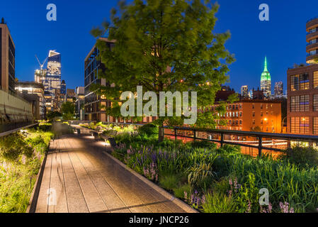 High Line promenade at twilight with city lights and illuminated skyscrapers. Chelsea, Manhattan, New York City Stock Photo