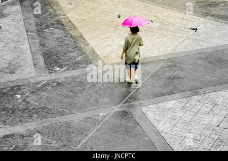 A lone unrecognizable woman walking alone in the deserted place showing the effects of lockdowns, social distancing and quarantine due to covid-19 Stock Photo