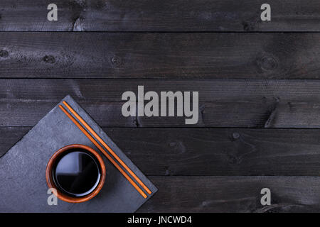 Soy sauce, chopsticks on black table. Top view with copy space Stock Photo