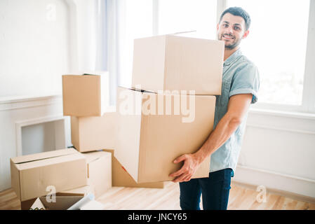 Smiling young man holds cardboard boxes in hands, housewarming. Moving to new house Stock Photo