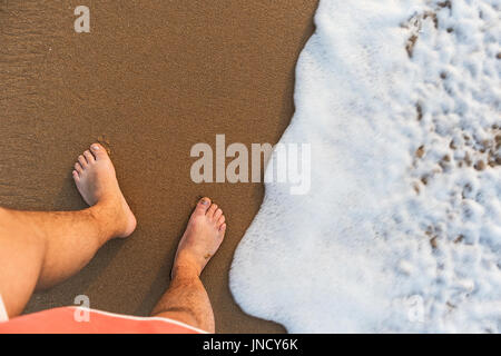 Man's feet seen from above with sea water. Stock Photo