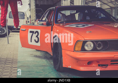 Orange race car waiting backstage for the race on a track. Vintage effect Stock Photo