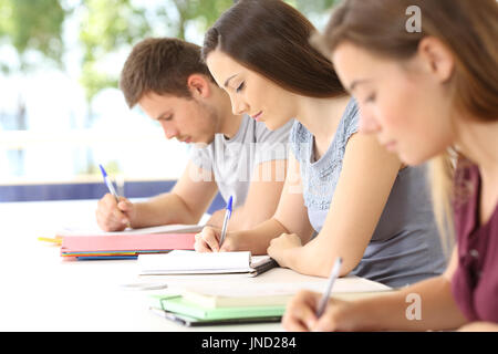 Three students taking notes during a class in a classroom Stock Photo