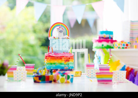 Kids birthday party decoration and cake. Decorated table for child birthday celebration. Rainbow unicorn cake for little girl. Room with festive ballo Stock Photo
