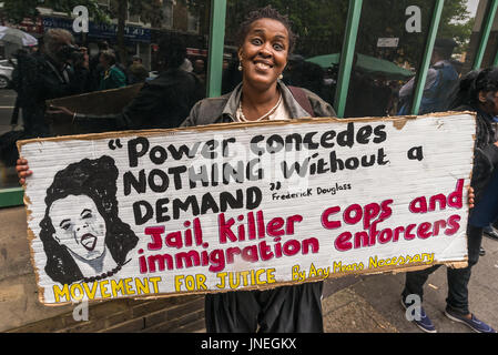 July 29, 2017 - London, UK - London, UK. 29th July 2017. A protesters holds a Movement fro Justice poster calling for killer cops to be jailed outside Stoke Newington Police Station at the protest for Rashan Charles, who died when two police handcuffed him and held him on the floor at a shop on the Kingsland Rd in the early hours of Saturday 22nd July. His family are determined to get answers about his death but call for everyone to act within the law. Members of the Charles family came to the protest along with family of Edson da Costa, who died after arrest in East Ham in June. Protesters he Stock Photo